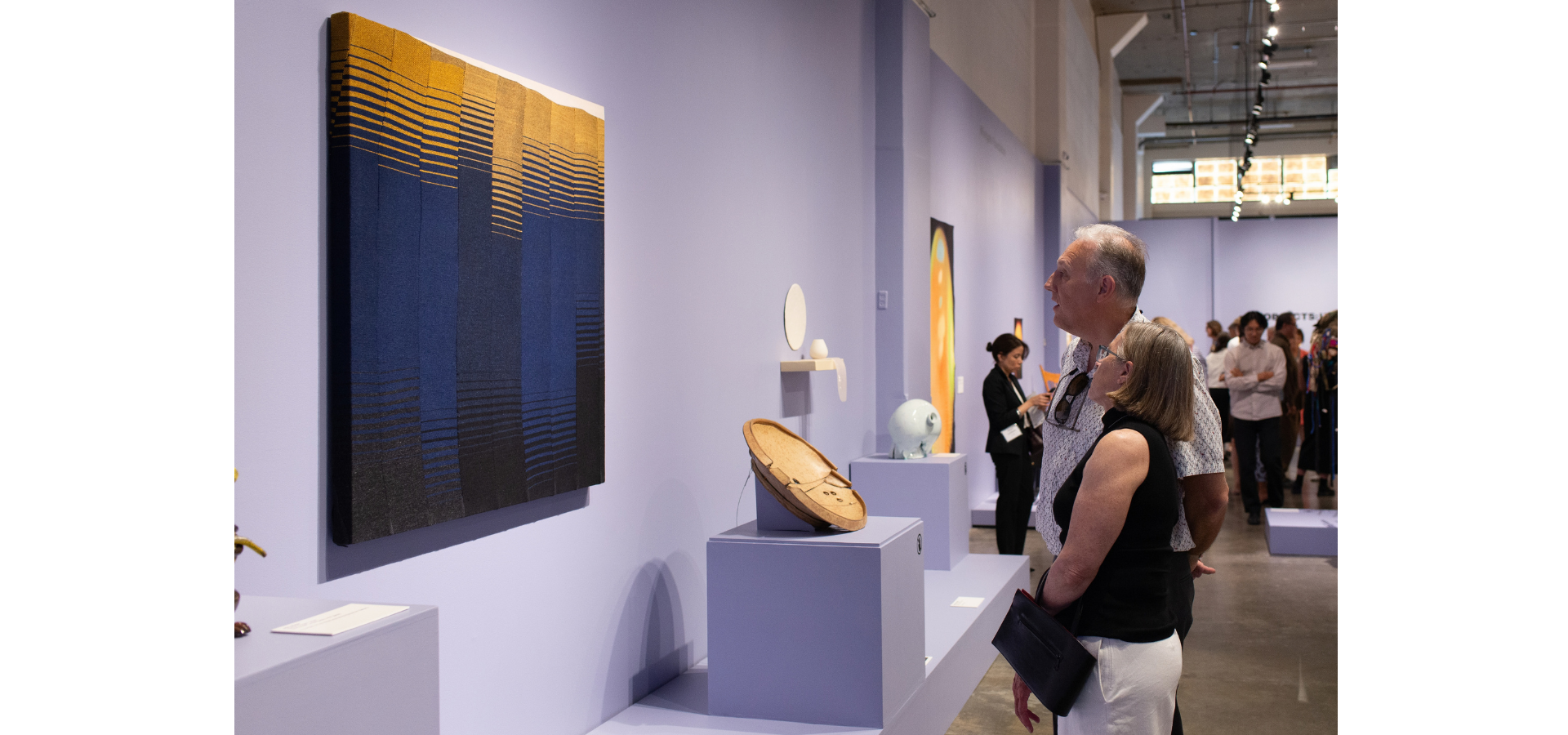 People look at textile artwork in OBJECTS: USA exhibition.