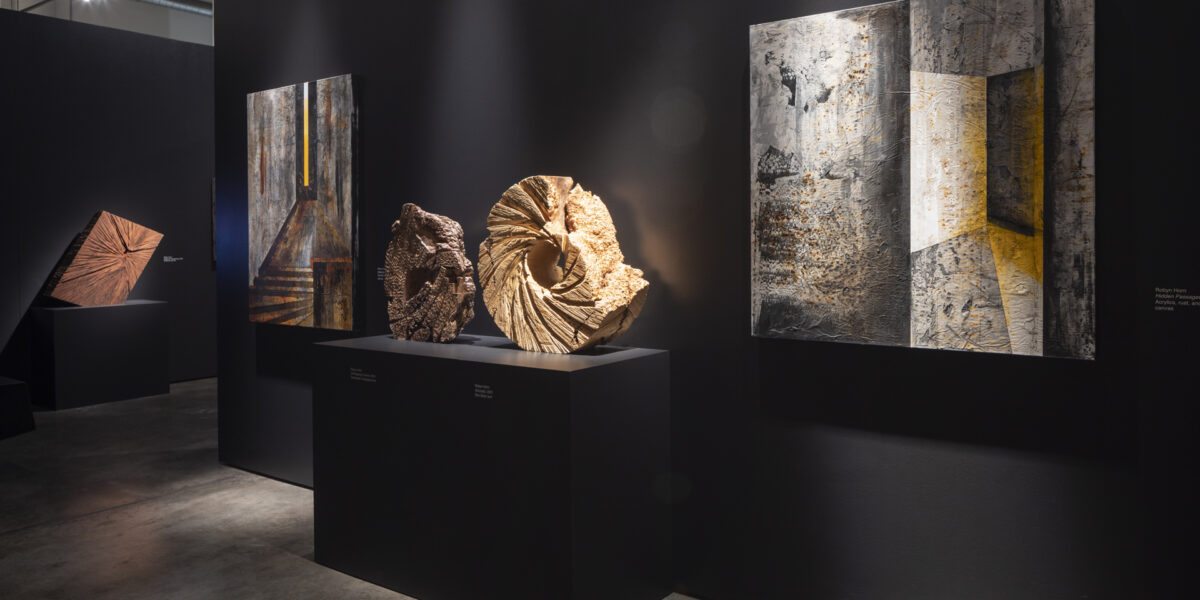 Interior shot of exhibition with wooden sculptures and abstract paintings