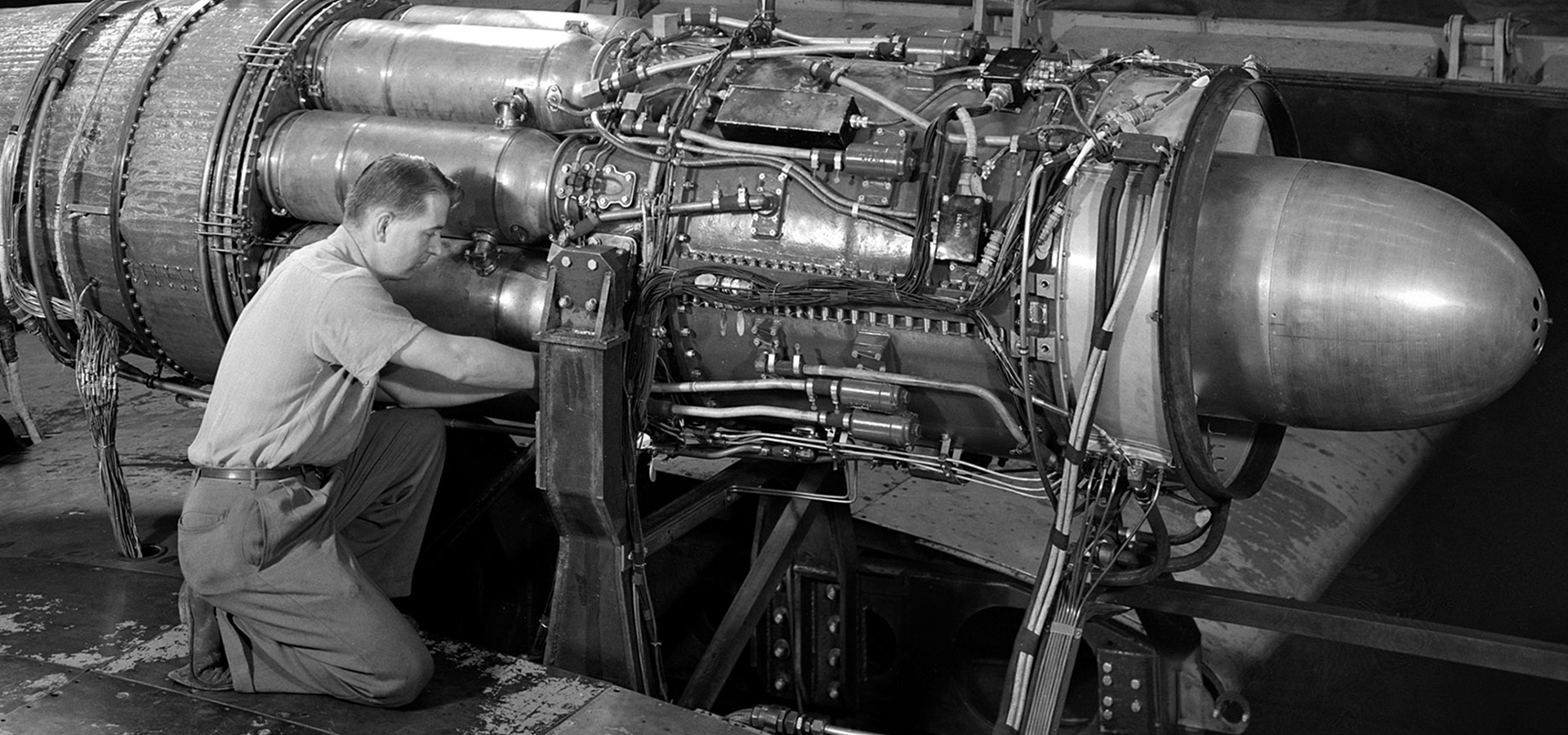 Guy kneeling working on a jet engine