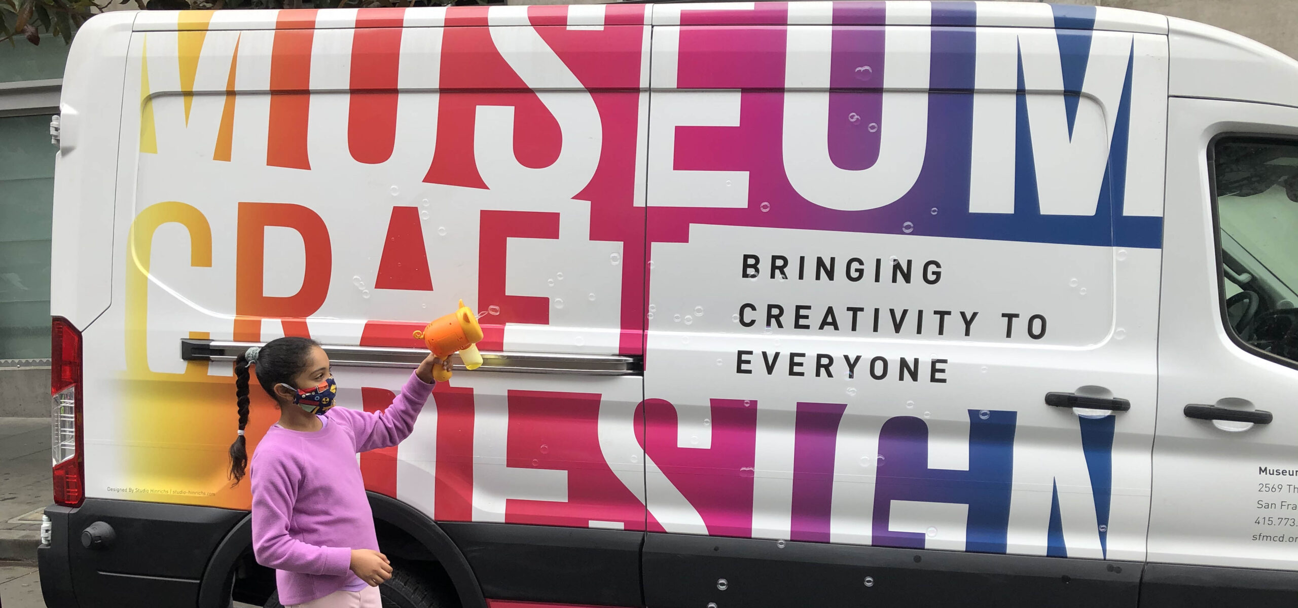 White van with rainbow museum and little girl with bubble gun