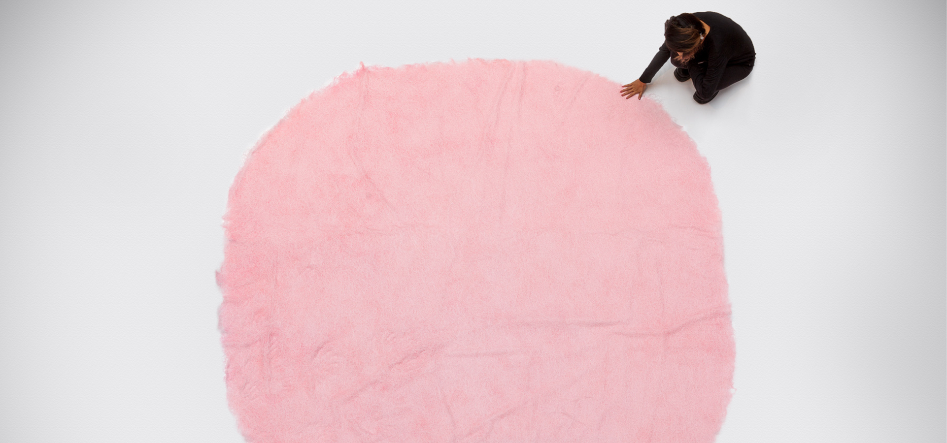 Overhead of a person touching a round pink knitted thread installation