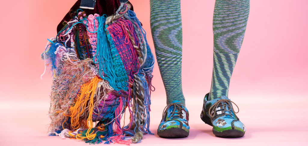 Colorful textile bag hanging down next to legs and shoes