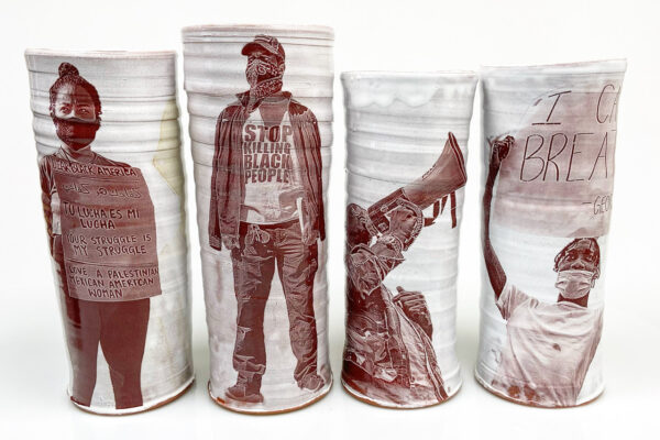 Cream cylindrical vases with impressed sepia photographs on their surface.