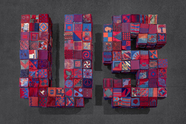 A quilted collage of squares in red, blue, and pink.