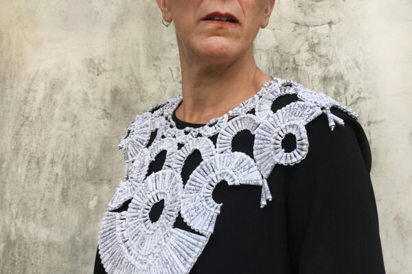 A woman wears an ornate lace-looking white collar.