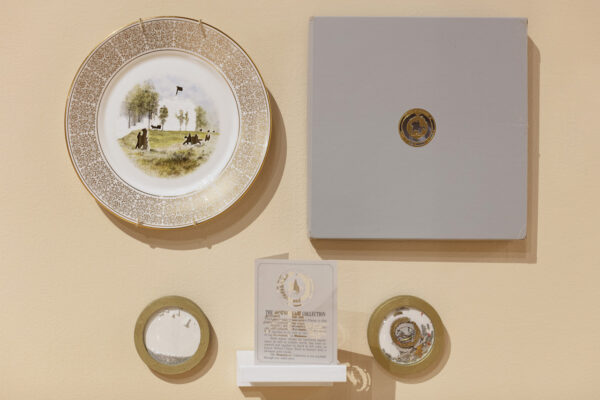 A row of porcelain plates and plaques mounted on a wall.