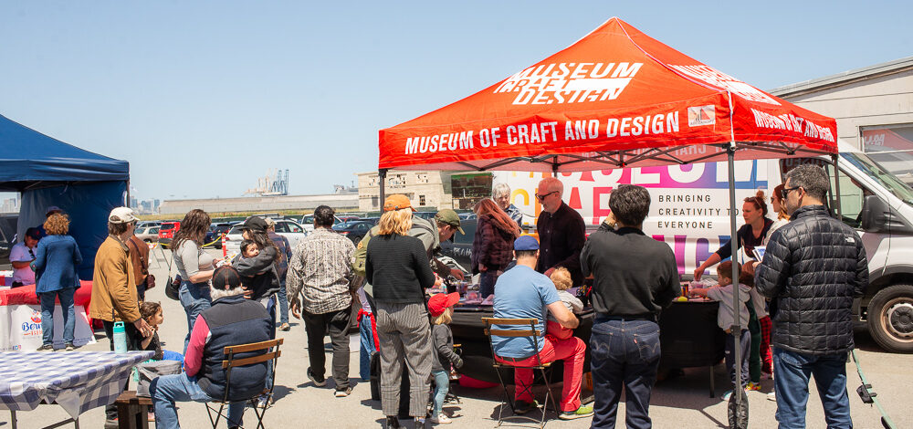 Photo of people at an outdoor event at tables under tents.