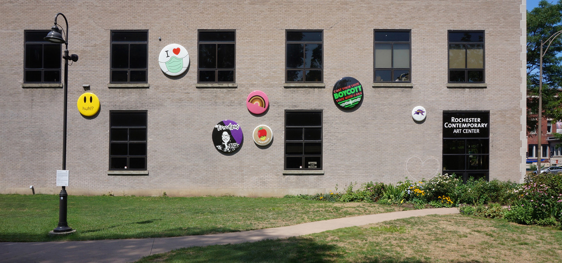 large scale button/pins mounted on facade of concrete wall with windows