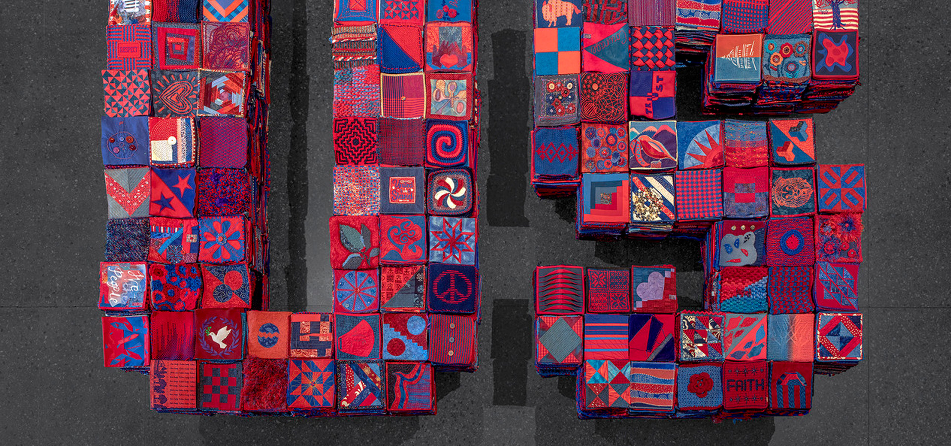 A quilted collage of squares in red, blue, and pink.