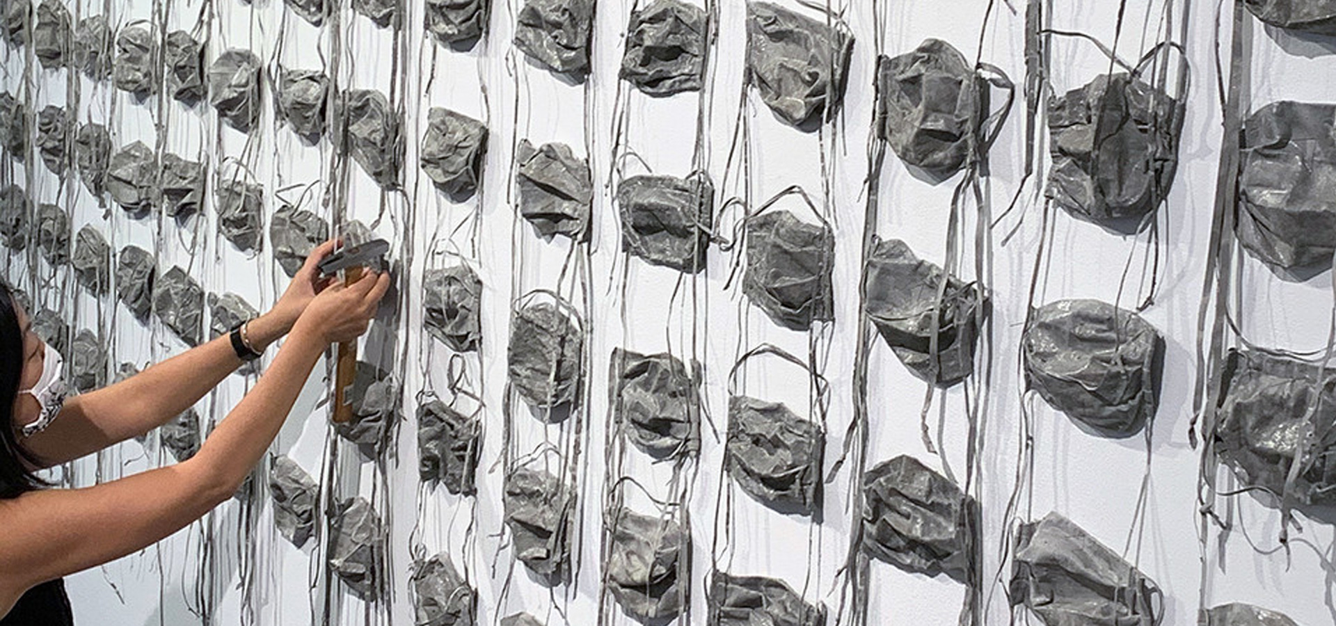 Rows of concrete surgical face masks mounted on a wall.