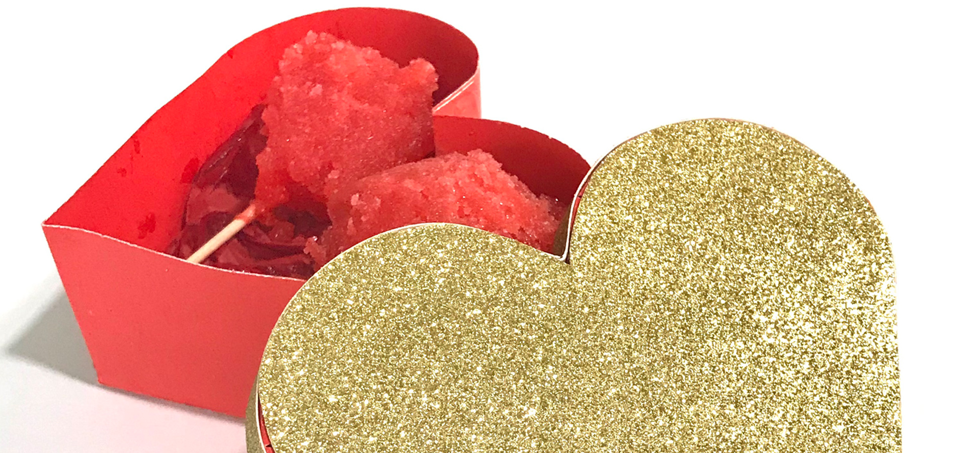 A heart-shaped red box with a gold glitter top