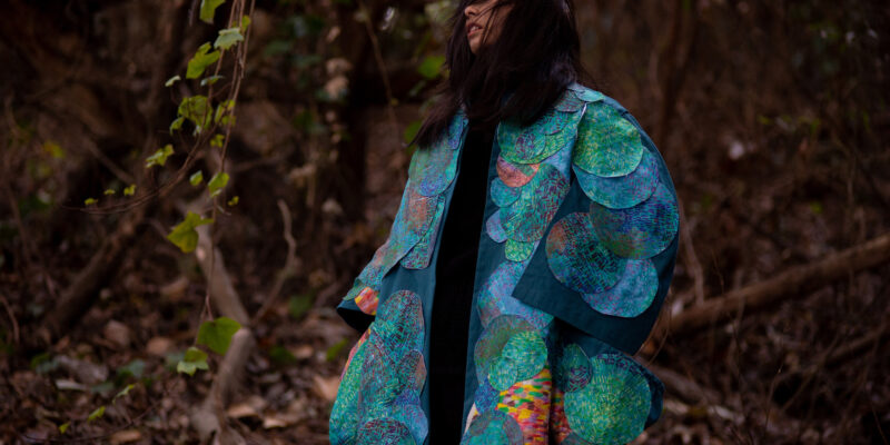 Female in woods modeling blue textile coat
