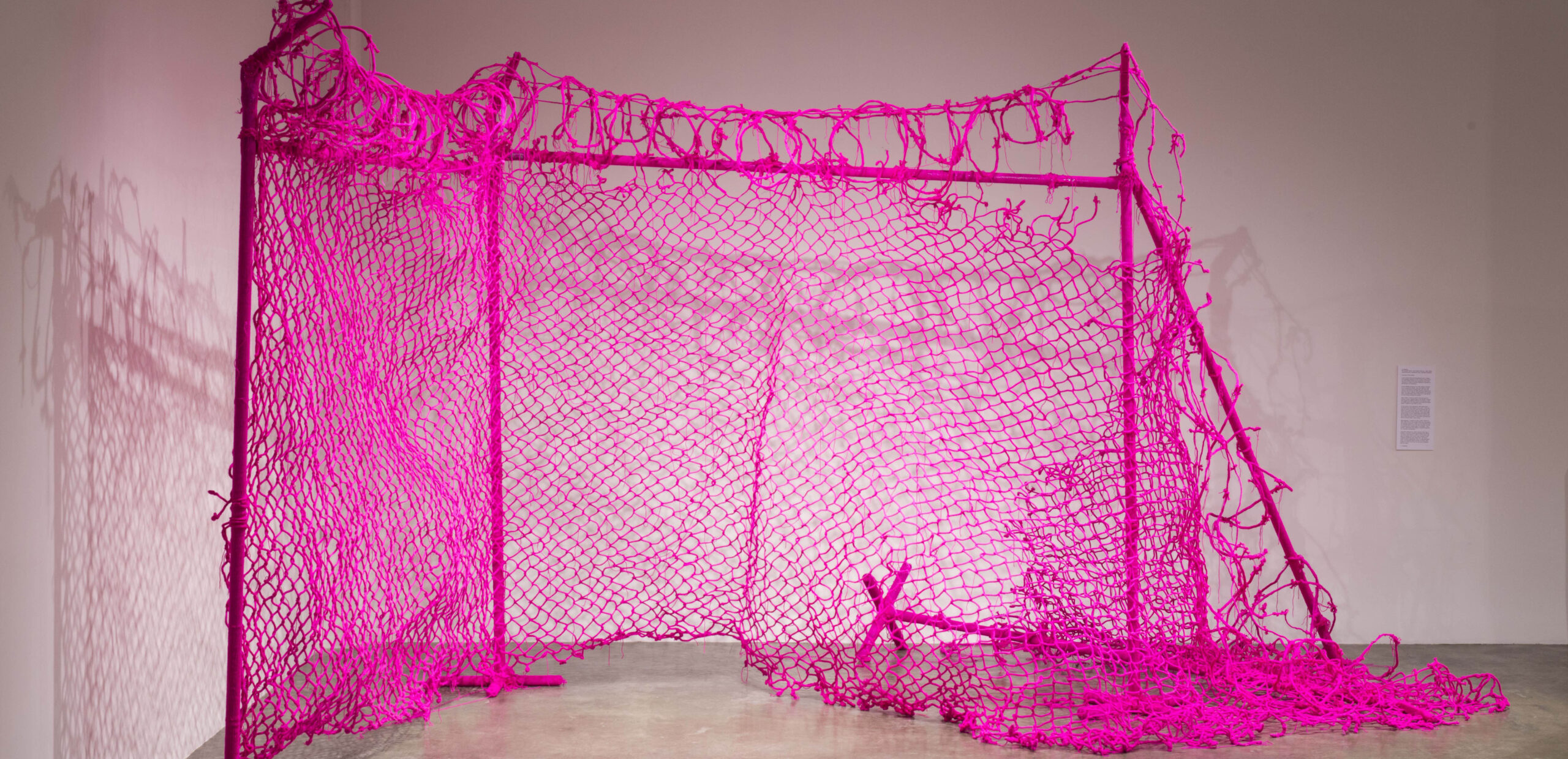 Large scale barbed wire fence made of hot pink yarn