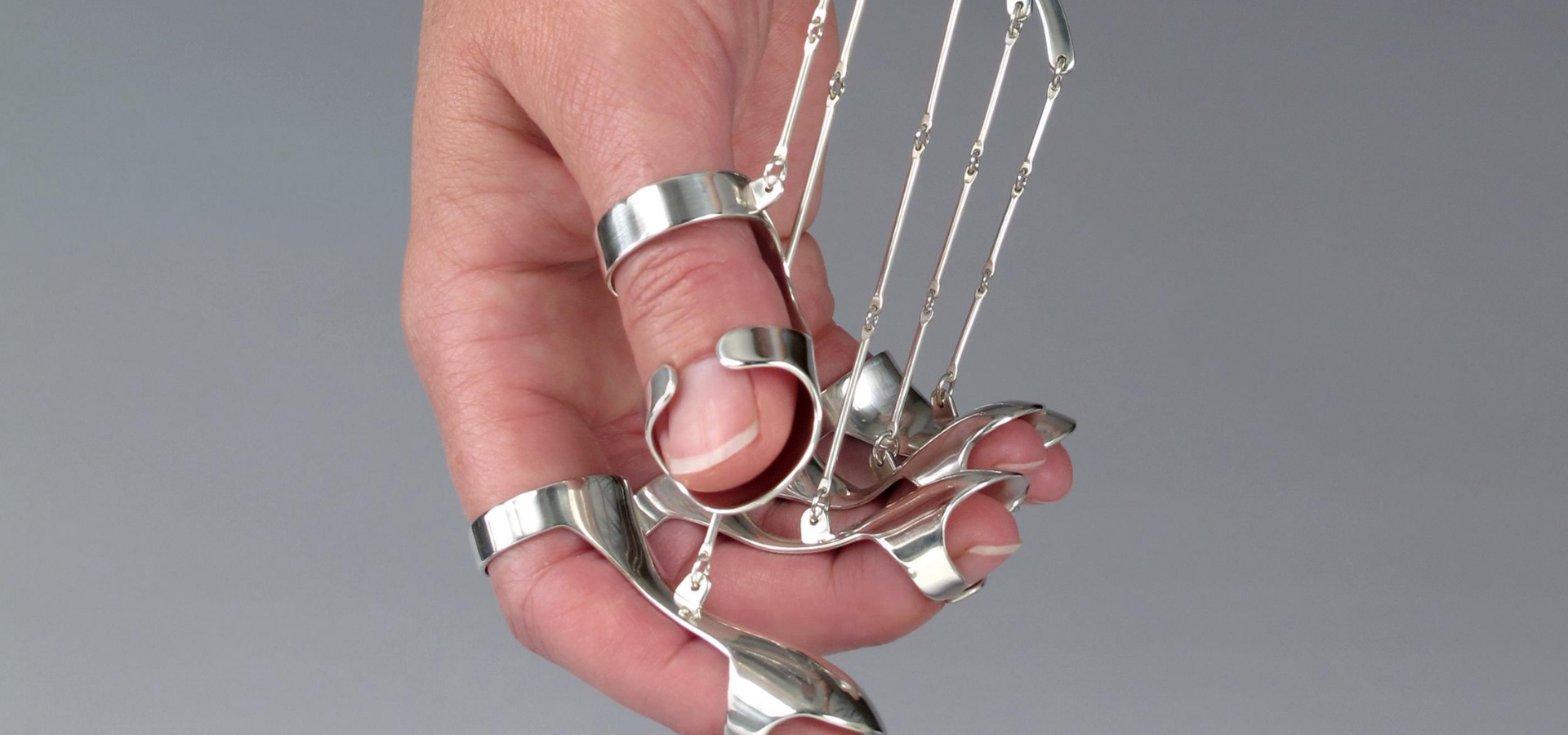 Silver jewelry art wrapped on finger and connected to wrist
