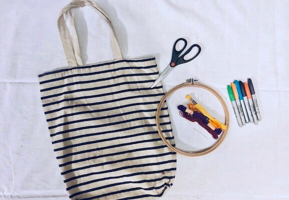 Altering a tote bag using sharpies, fabric markers, and embroidery floss.