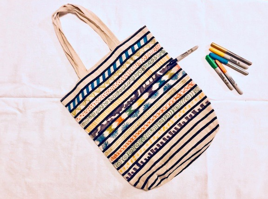Altering a tote bag using sharpies, fabric markers, and embroidery floss.
