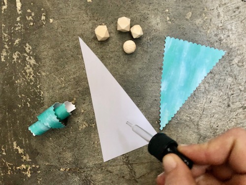 Using a dropper to apply essential oil to a paper triangle.