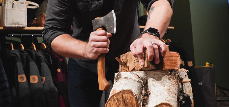 Hands holding axe cutting a piece of wood