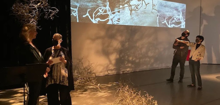 Visitors looking at projections on walls and projection mapping that overlays onto the floor.