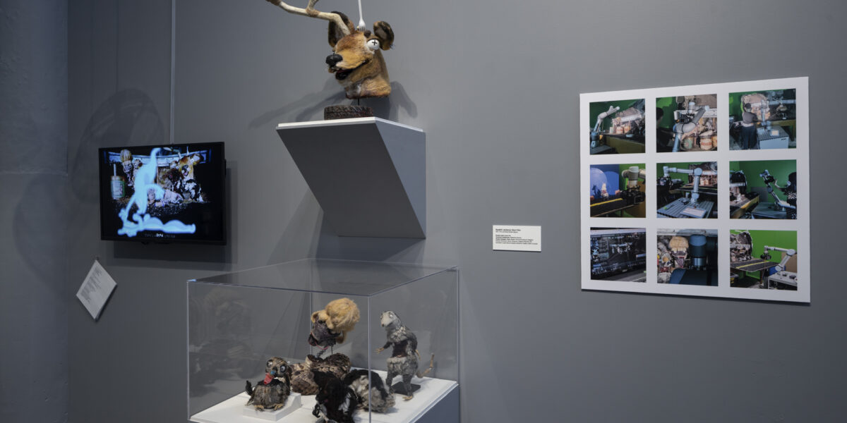 Photo of exhibition in a museum with hand made animal puppets and work on the wall.