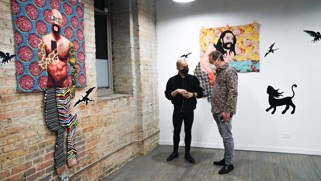 Two people talking in an artist studio with art hanging on the wall.