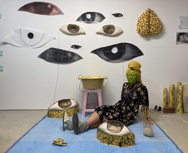 Portrait of Cathy Lu sitting among her artwork
