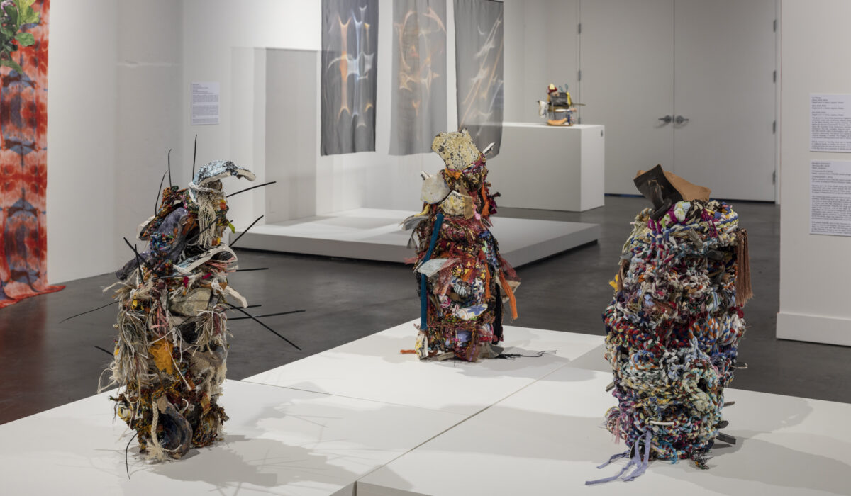Three multi-media artwork sculptures on pedestal in museum
