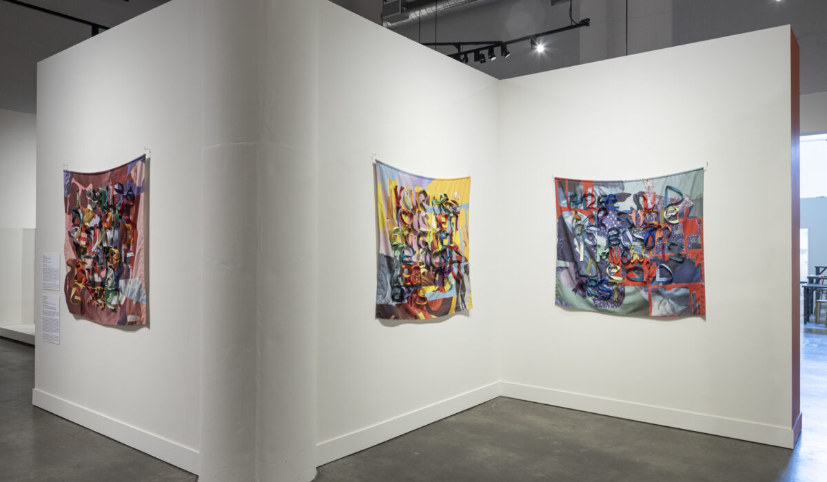 Installation view of several artworks made of hanging fabric and zippers