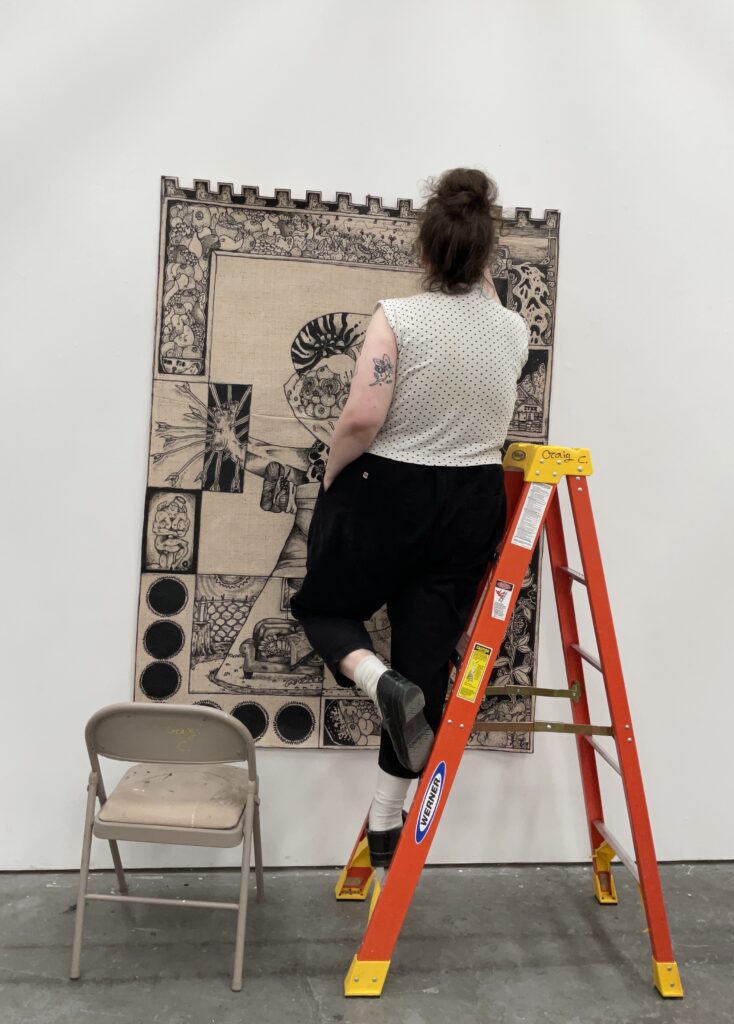 Person standing on ladder in front of artistic tapestry print