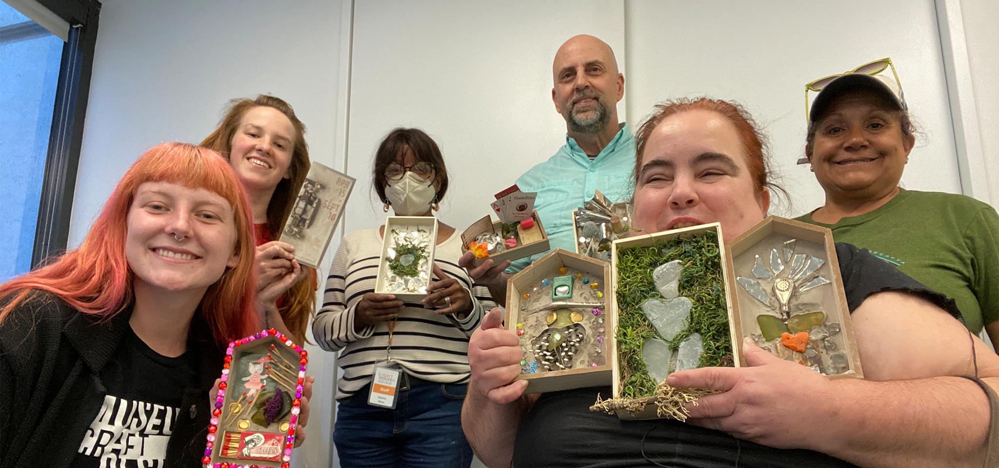 A group photo of people holding up their finished crafts from the last Acces After Hours