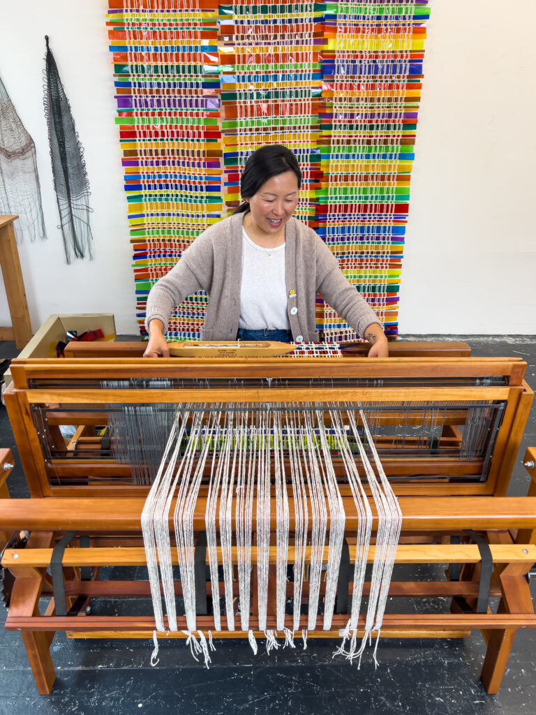 Photo of an artist in front of a weaving loom