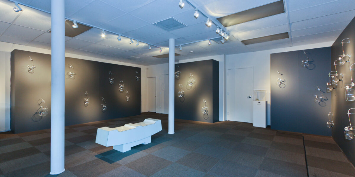 View of the inside of an exhibition with grey walls and pe
