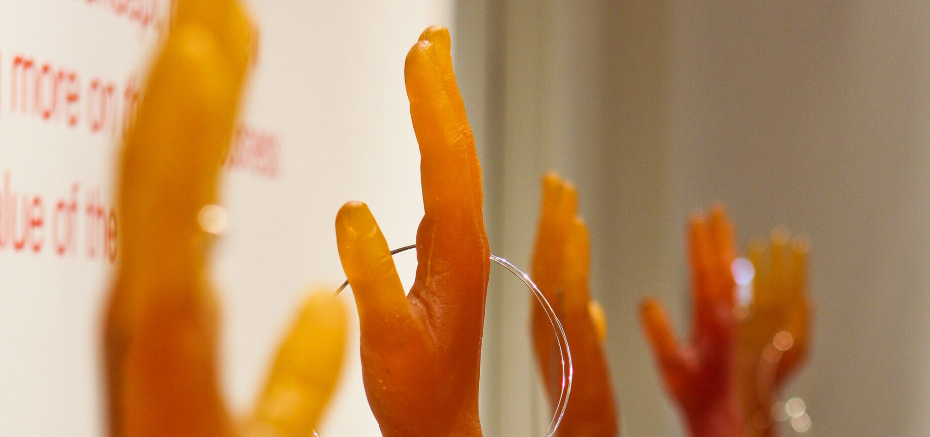 an exhibition photo of five orange sculptures of hands