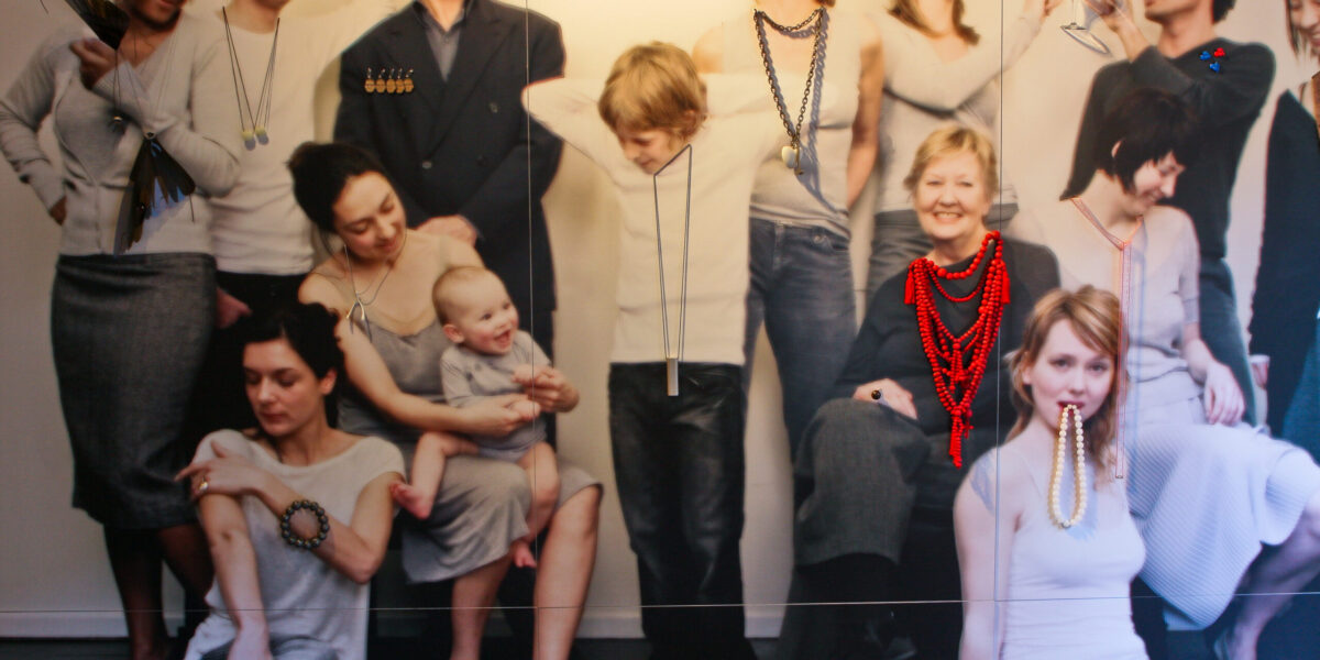 An exhibition photo of a wall with a large photo of a family with necklaces