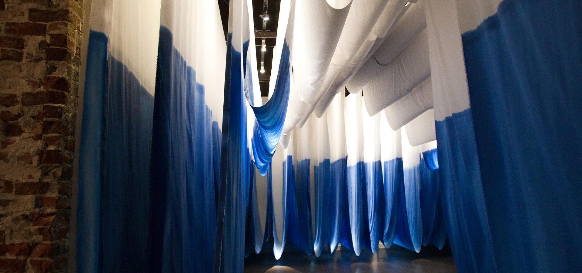 Large draping fabric throughout the museum. Fabric is white on top and blue on the bottom.