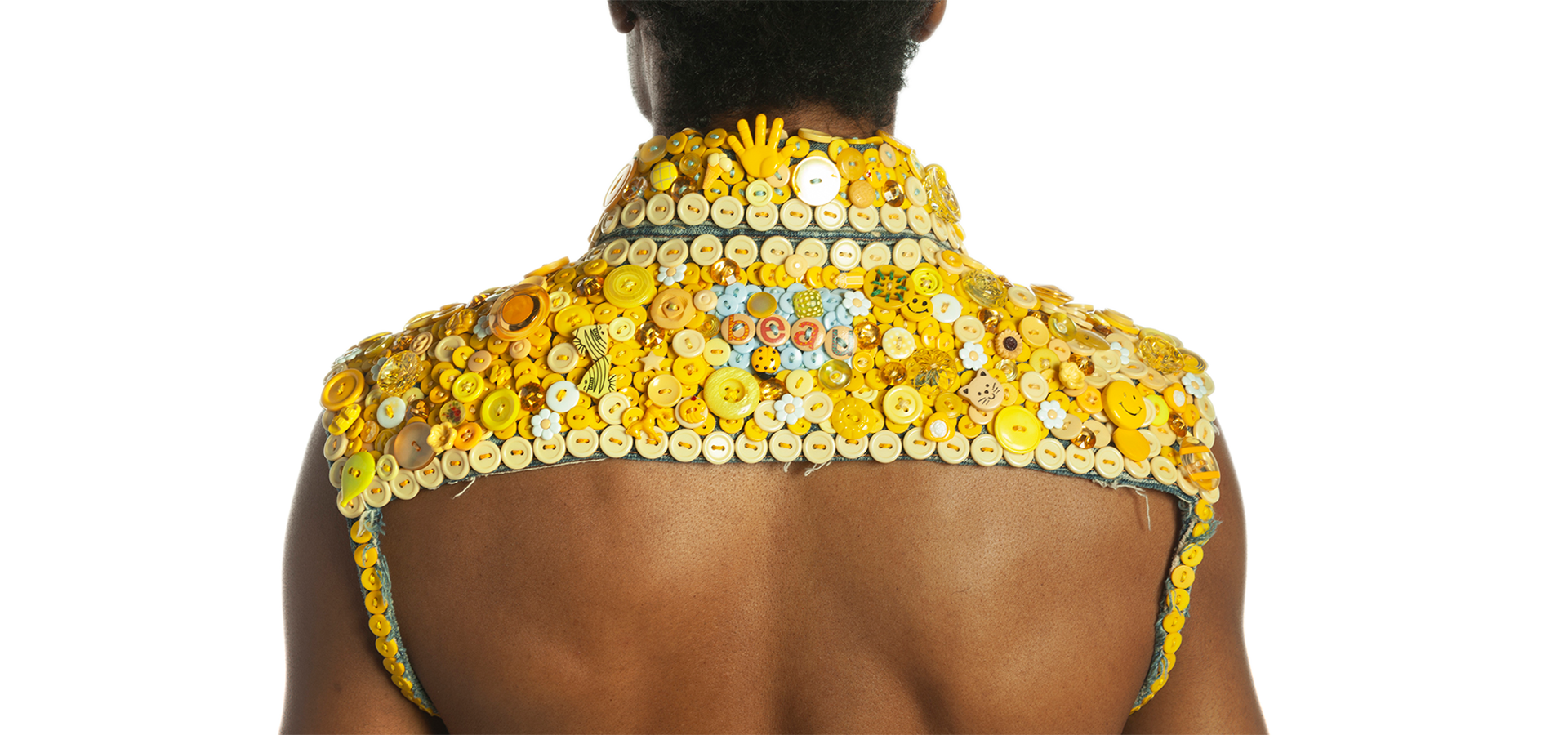 Close up photo of the back of a person wearing a cropped yellow jacket made from yellow buttons