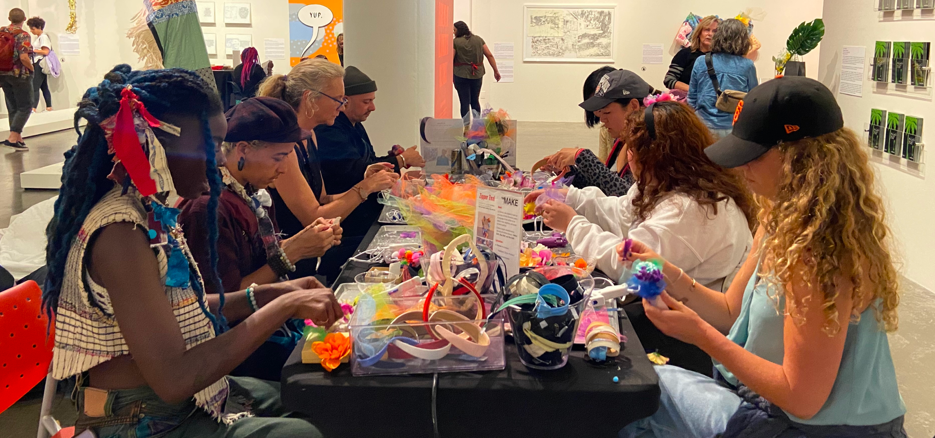 Photograph of people sitting at a table engaging with a MakeArt activation at MCD's gallery