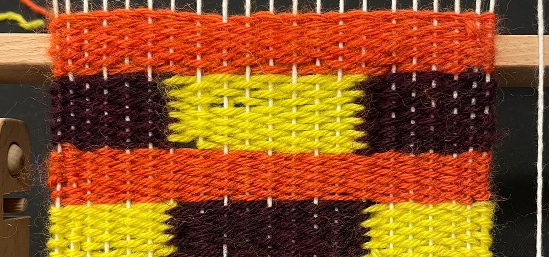 Photograph of weaving project using orange, yellow, and brown threads