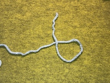 Step 1, instruction #1 Create a loop in your yarn with the shorter end of the yarn crossing over top of the long end towards the side furthest from you.