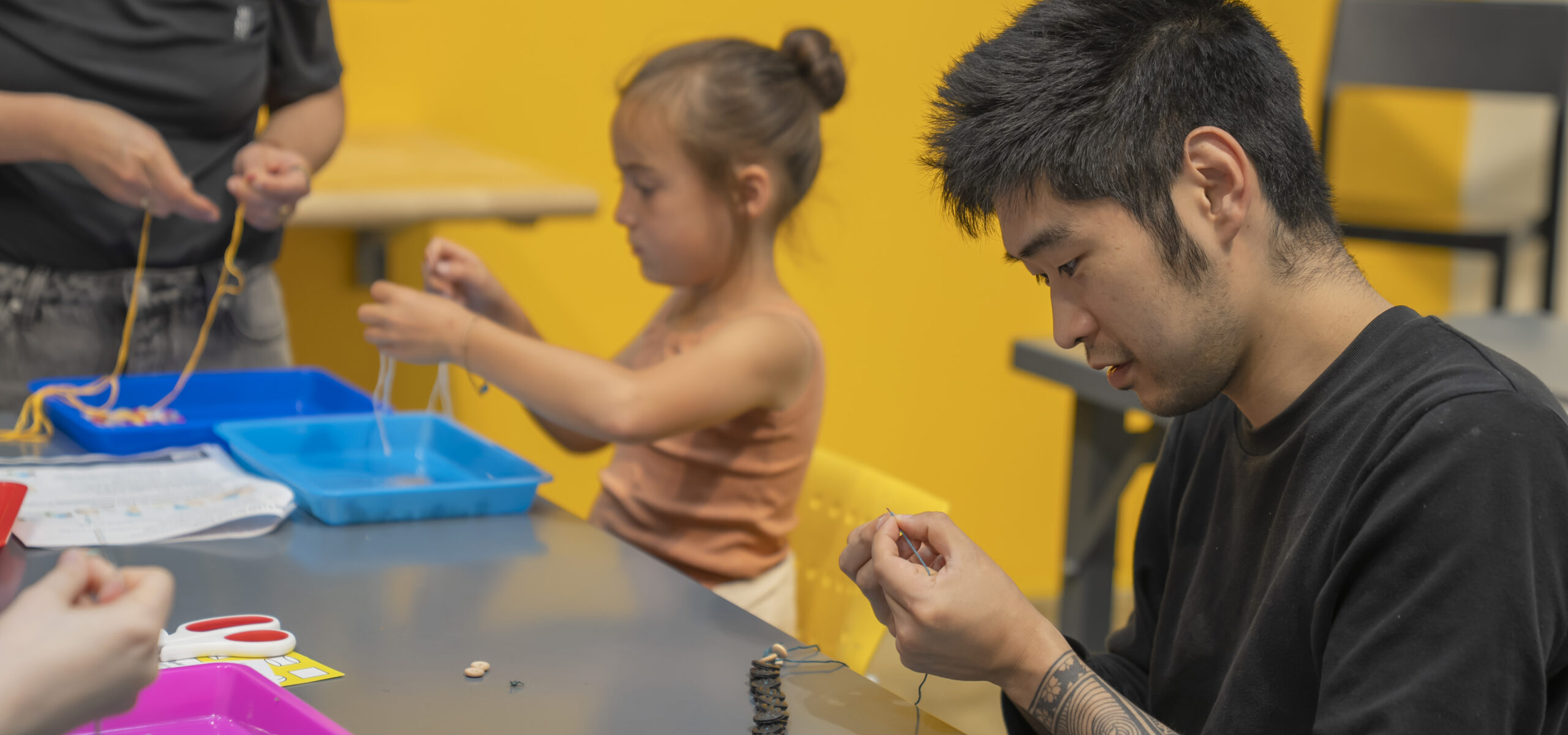 People crafting button necklaces in a museum space