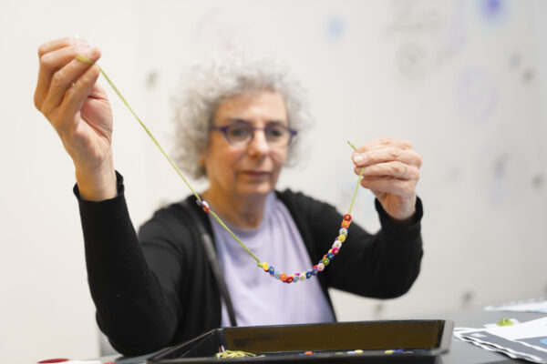 People crafting button necklaces in a museum space