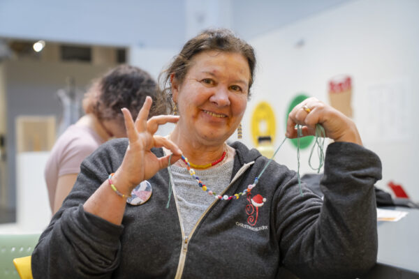 People crafting button necklaces in a museum space