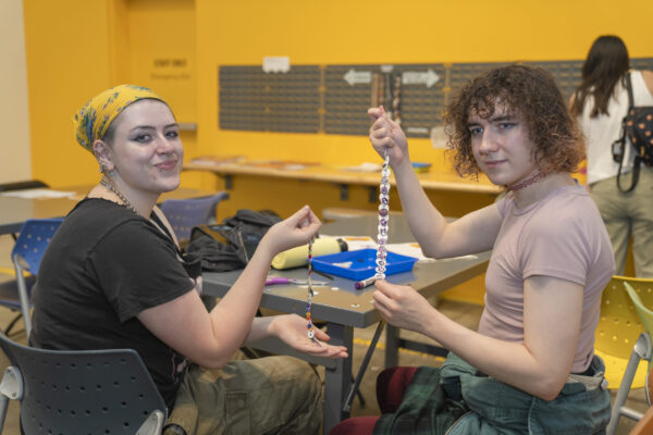People crafting button necklaces in a museum space