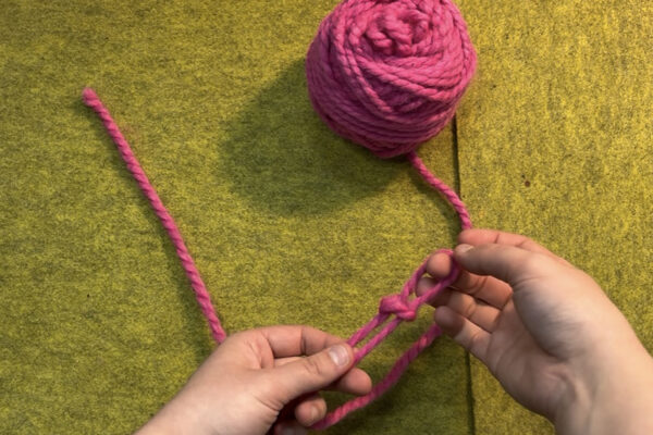 Section 1 - Casting On | Long Tail Method: Step 2 - Tie a Slip Knot: 3. Pull pinched yarn through original loop to form slip loop. You should now have what resembles a loop with a belt around it, and two tails pointing the same direction. 4. Pull up on loop to tighten its “belt.” 5. Check slip knot. Your slip knot is tied correctly if you can pull on the longer tail (working yarn) and tighten your loop - if you pull too tight your knot will unravel.