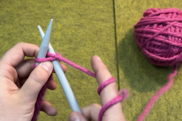 Section 2 - Knit Stitch: How to Knit: 6. Using working yarn around your index finger, wrap yarn around the tip of right needle from back to front (counterclockwise).