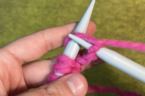 Section 2 - Knit Stitch: How to Knit: 7. Angle right needle down and towards you. This should expose the loop made by the first stitch and working yarn.
