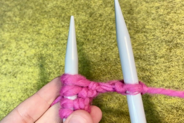 Section 2 - Knit Stitch: How to Knit: 9. Drag needle up to slip the loop off of the left hand needle and onto the right. Lightly pull working yarn to tighten if necessary.