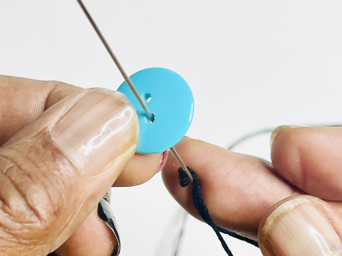 Step 4 - Thread Remaining Buttons: 1. Place the needle through the first buttonhole. 2. Place the needle through the second buttonhole.