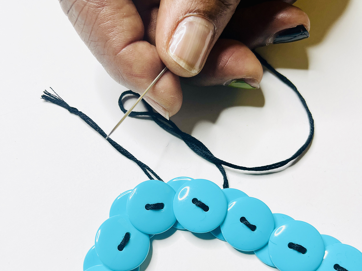 Step 6 - Join Necklace Ends Together: 1. Place a needle through the first and second buttonholes of the original button.