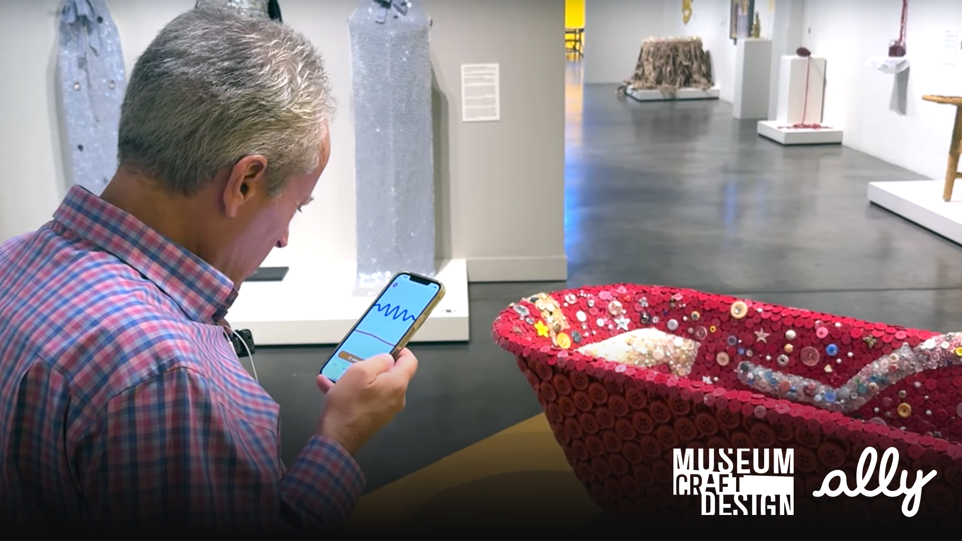 Photo of a person with a phone listening to an audio description in a museum exhibition